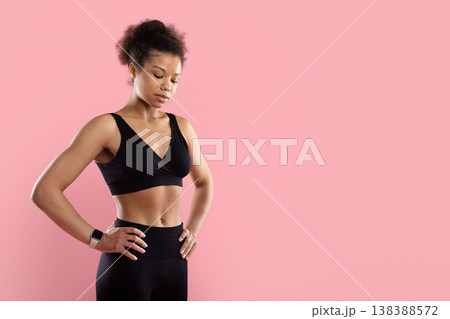 Focused Black sportswoman standing with hands on hips looking down Focused Black sportswoman standing with hands on hips looking down 138388572