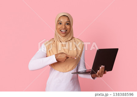 Young black Muslim woman in hijab pointing excitedly at laptop in hands 138388596