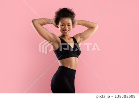 Fit black sportswoman in black sports bra posing with hands behind head Fit black sportswoman in black sports bra posing with hands behind head 138388609