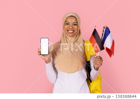 Black Muslim woman student in hijab holding blank smartphone and international flags Black Muslim woman student in hijab holding blank smartphone and international flags 138388644