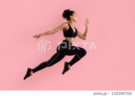 Athletic black woman performing dynamic running jump in sportswear on pink background Athletic black woman performing dynamic running jump in sportswear on pink background 138388708