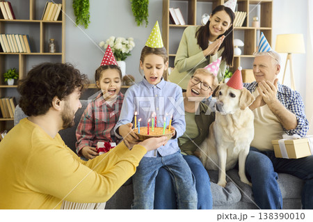 Multigenerational family birthday party at home with cake, candles, gifts and dog Multigenerational family birthday party at home with cake, candles, gifts and dog 138390010