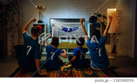 Family celebrating football goal while watching match on TV at home together 138390059