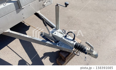 Close up of a professional galvanized trailer hitch mechanism with jockey wheel on asphalt surface Close up of a professional galvanized trailer hitch mechanism with jockey wheel on asphalt surface 138391085