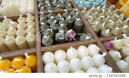 Close up of various colorful handmade wax candles neatly organized in a wooden divider box display Close up of various colorful handmade wax candles neatly organized in a wooden divider box display 138391086