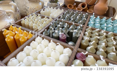 Handmade colorful wax taper candles in a wooden organizer near rustic ceramic jars in a boutique shop Handmade colorful wax taper candles in a wooden organizer near rustic ceramic jars in a boutique shop 138391095