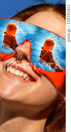 Woman in red sunglasses with cold beer glasses reflected in lenses smiling outdoors. Woman in red sunglasses with cold beer glasses reflected in lenses smiling outdoors. 138391821