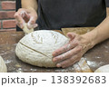 バヌトン（発酵カゴ）から出したカンパーニュ生地にクープを入れるパン職人の手元 138392683