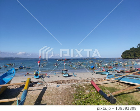 Colorful fishing boats rest under a bright blue sky on a peaceful tropical beach. Colorful fishing boats rest under a bright blue sky on a peaceful tropical beach. 138392809