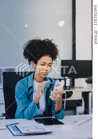 Young African American black woman working on laptop and mobile phone Young African American black woman working on laptop and mobile phone 138392945