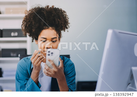 Young African American black woman working on laptop and mobile phone Young African American black woman working on laptop and mobile phone 138392947