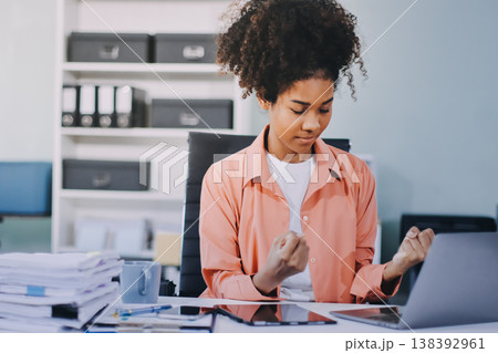 Smiling businesswoman working on laptop in office 138392961
