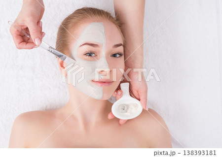 Face mask apply, spa beauty treatment, skincare. Woman getting facial care by beautician at spa salon, top view 138393181