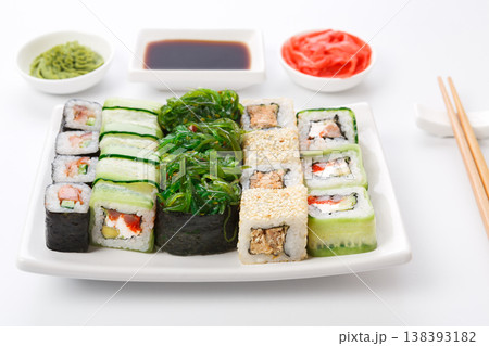 Traditional japanese food restaurant. Sushi set on white plate, soy sauce, ginger, wasabi and chopsticks aside. Colorful rolls and gunkan assortment at white background, pov 138393182