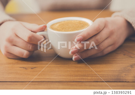Enjoy cup of coffee. Woman hands closeup with aromatic espresso or americano on wood table Enjoy cup of coffee. Woman hands closeup with aromatic espresso or americano on wood table 138393291