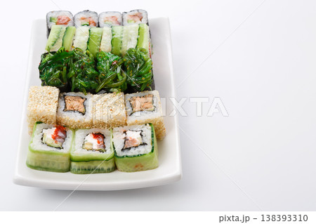Traditional japanese cuisine background with copy space. Fish and vegetable gunkans and rolls. Sushi set on white plate Traditional japanese cuisine background with copy space. Fish and vegetable gunkans and rolls. Sushi set on white plate 138393310