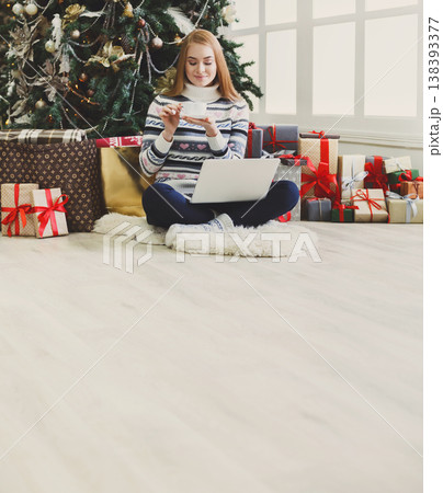 Christmas online shopping. Woman has coffee, buy presents on laptop, prepare to xmas, among gift boxes and packages. Winter sales Christmas online shopping. Woman has coffee, buy presents on laptop, prepare to xmas, among gift boxes and packages. Winter sales 138393377