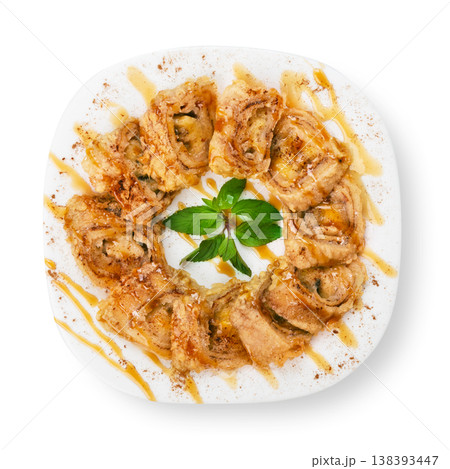 Banana pastry rolls with caramel sauce - restaurant dessert on a square plate isolated at white background Banana pastry rolls with caramel sauce - restaurant dessert on a square plate isolated at white background 138393447
