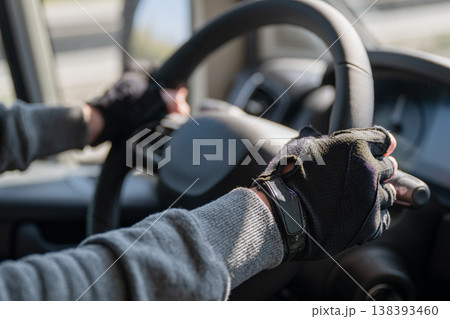 Driver hands on steering wheel wearing gloves inside car interior close up safe driving transportation concept 138393460