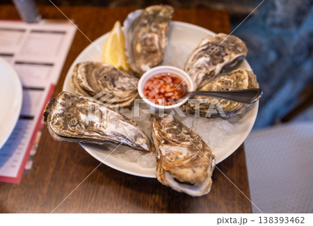 Fresh oysters on ice with lemon and sauce served on plate gourmet seafood appetizer restaurant dining concept 138393462