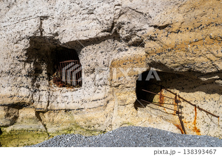 Chalk cliff caves with rusty metal grates on coastal rock wall weathered geology texture seaside landscape concept 138393467