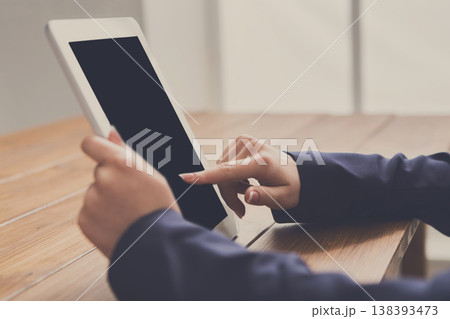 Female using digital tablet while sitting at wooden table, close-up, side view, copy space on the screen Female using digital tablet while sitting at wooden table, close-up, side view, copy space on the screen 138393473