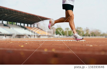 Runner Legs Running on Athletics Track in Stadium 138393646