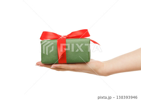 Woman's hands give present in paper with red ribbon, isolated on white background, close-up, cutout Woman's hands give present in paper with red ribbon, isolated on white background, close-up, cutout 138393946