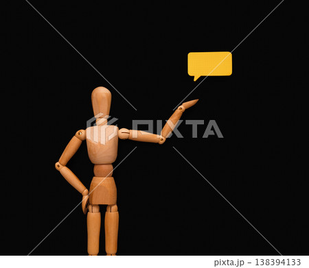 Handcrafted wooden man figure mannequin model dummy doll pointing on blank speech bubble, presenting creative idea or business solution on black studio background, copy space, objects, nobody 138394133