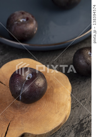 several beautiful clean black plums on the table, the plums are covered with a lot of drops of water 138394574