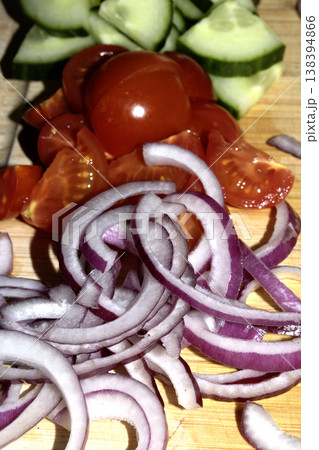 Close up of finely chopped sliced red onion salad vegetables on wooden chopping board Close up of finely chopped sliced red onion salad vegetables on wooden chopping board 138394866