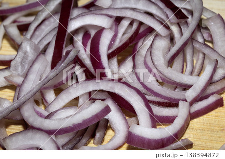 Close up of finely chopped sliced red onion salad vegetables on wooden chopping board 138394872