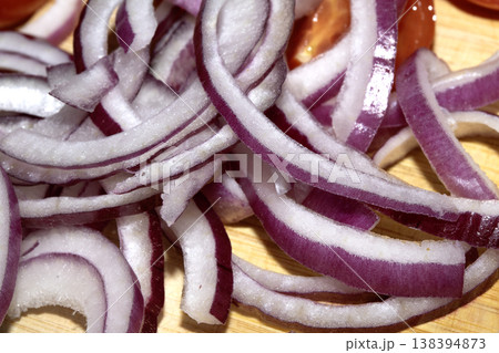 Close up of finely chopped sliced red onion salad vegetables on wooden chopping board Close up of finely chopped sliced red onion salad vegetables on wooden chopping board 138394873