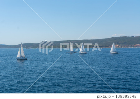 Group of sailboats sailing near coastline on sunny day. Summer travel and marine leisure concept 138395548