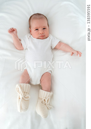 Infant in minimal white outfit on clean background. Concept of baby fashion, organic cotton clothing and newborn apparel branding. Infant in minimal white outfit on clean background. Concept of baby fashion, organic cotton clothing and newborn apparel branding. 138395591