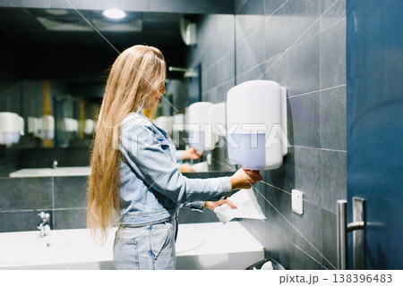 Customer Using Paper Dispenser in Public Bathroom 138396483