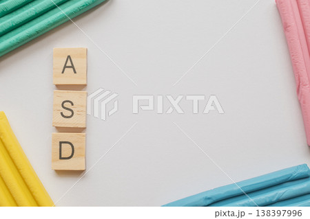 Top view photo of the ASD acronym in wooden tiles on a white background. Vibrant clay accents symbolize the autism spectrum, with ample copy space for medical or social content 138397996