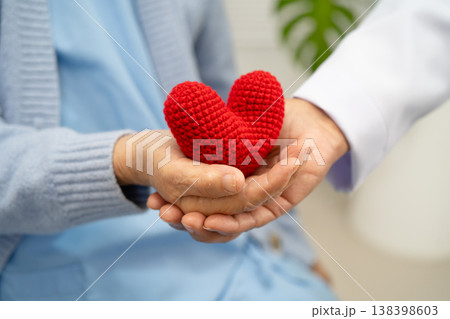 Doctor giving a red heart to senior patient in hospital. Doctor giving a red heart to senior patient in hospital. 138398603
