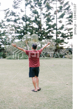 Energetic pose with hands raised in open green space Energetic pose with hands raised in open green space 138401107