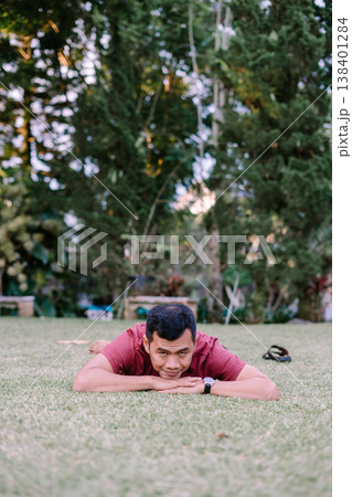 Man lying face down relaxing on green grass field Man lying face down relaxing on green grass field 138401284