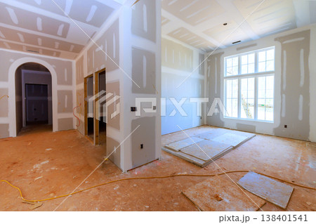 Workers are preparing new home interior with drywall, bare floors in room with large windows. 138401541