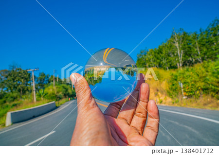 Hand Holding a Crystal Ball Showing a Journey Through a Mist Covered Valley Hand Holding a Crystal Ball Showing a Journey Through a Mist Covered Valley 138401712