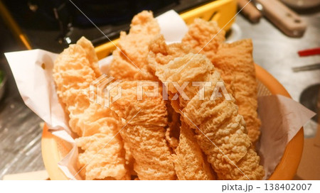 close up of a basket of crispy deep fried Beancurd sheet rolls ( bean curd skin) served on parchment paper with dipping sauces, which are ingredient for Cantonese hot pot.  138402007