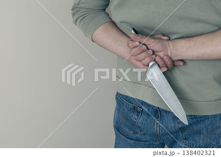 Man hiding kitchen knife behind back 138402321