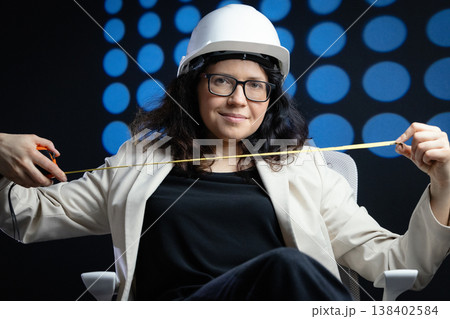 Woman engineer wearing hard hat holding measuring tape 138402584