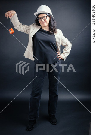 Woman wearing hard hat holding measuring tape 138402616