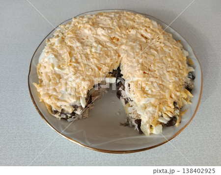 Layered mushroom salad mimosa style with grated cheese and mayonnaise topping, a traditional russian appetizer or festive dish on a white plate with a golden rim Layered mushroom salad mimosa style with grated cheese and mayonnaise topping, a traditional russian appetizer or festive dish on a white plate with a golden rim 138402925