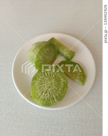 Green radish slices on white plate providing fresh, healthy, and organic vegetable inspiration for dieting, vegetarian, and plant-based nutrition concepts 138402926
