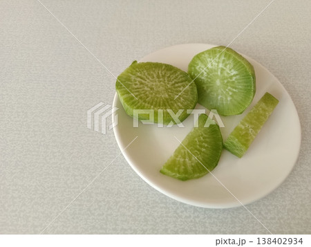 Green daikon radish slices presenting a vibrant, fresh ingredient ready for healthy cooking, preparing a nutritious salad, or using in a plant-based recipe 138402934