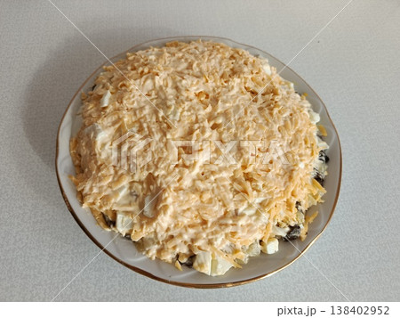 Layered salad with chicken, egg, prunes, walnuts, and mayonnaise dressing, topped with shredded hard cheese, prepared for a holiday meal or special occasion Layered salad with chicken, egg, prunes, walnuts, and mayonnaise dressing, topped with shredded hard cheese, prepared for a holiday meal or special occasion 138402952